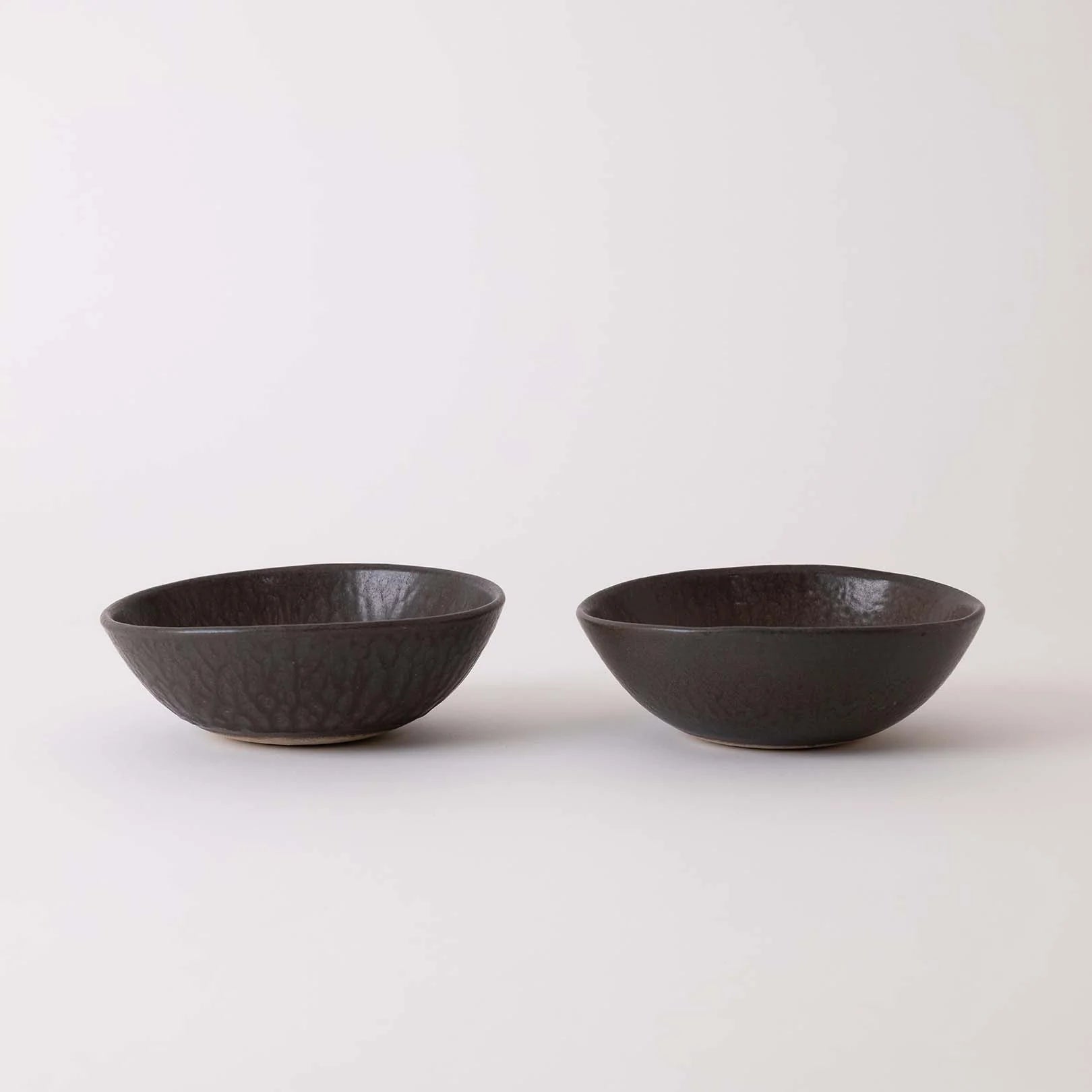 Two black ceramic bowls on a white background
